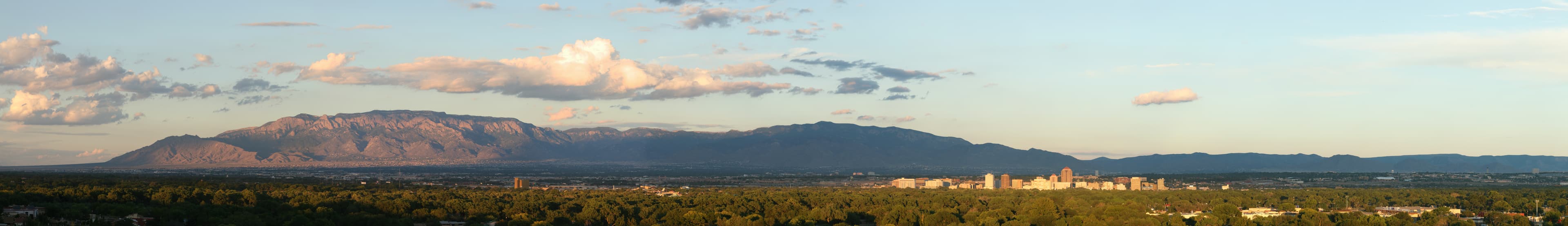 Panoramic sunset view of Albuquerque skyline with the Sandia Mountains in the background